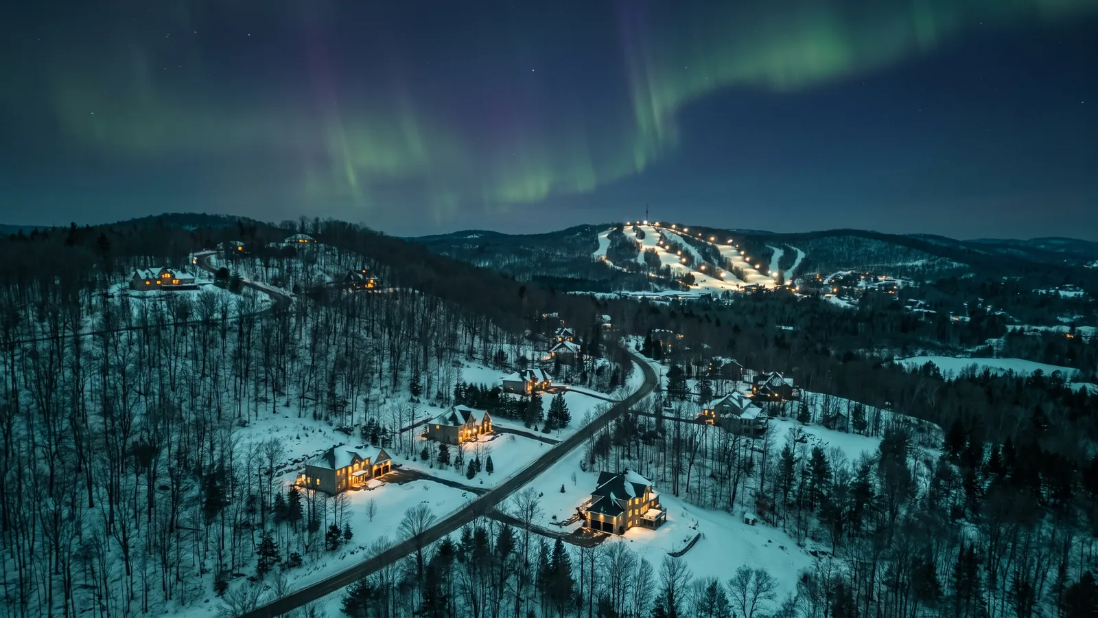 The wooded hills of Cantley with Mont-Cascades in the distance at dusk under the northern lights