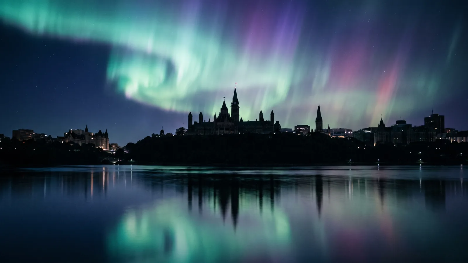 Ottawa's Parliament Hill at night under the northern lights, seen across the Ottawa River